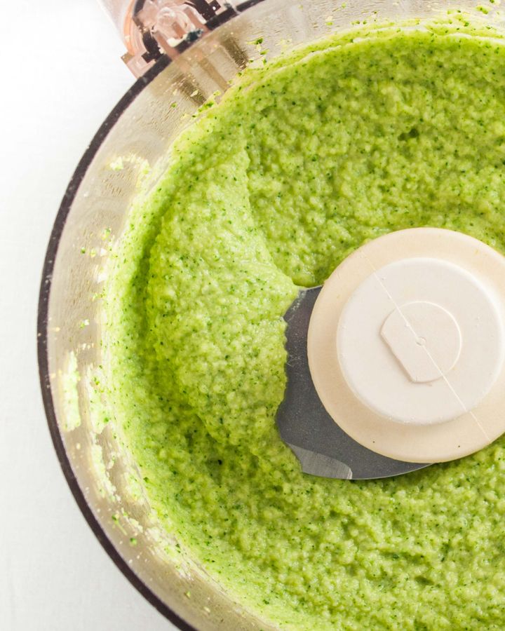 Close up of food processor with bright green broccoli purée