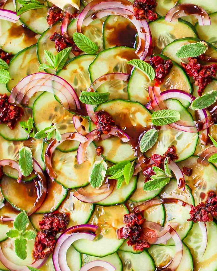 Close up of cucumber salad with harissa chilli paste, sliced red onion, fresh mint and pomegranate molasses