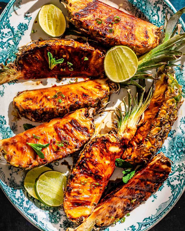 Wedges of pineapple with stems attached griddled until caramelised, on blue edged plate