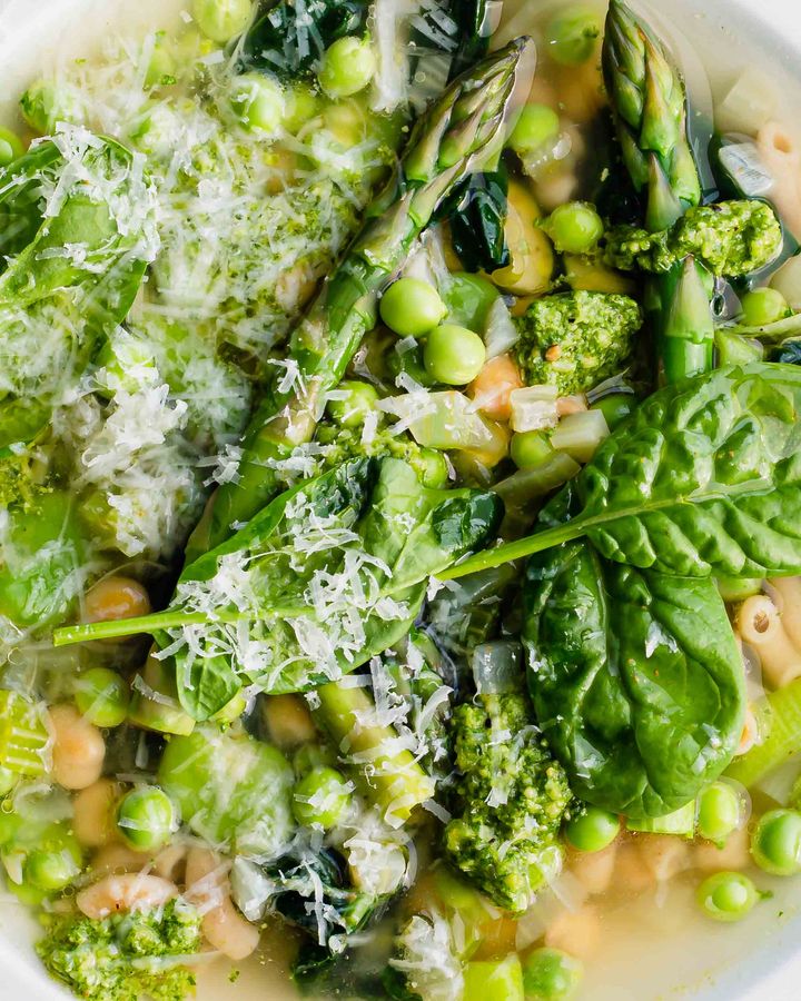 Close up of bright green spring vegetable minestrone soup with grated pecorino and fresh pesto