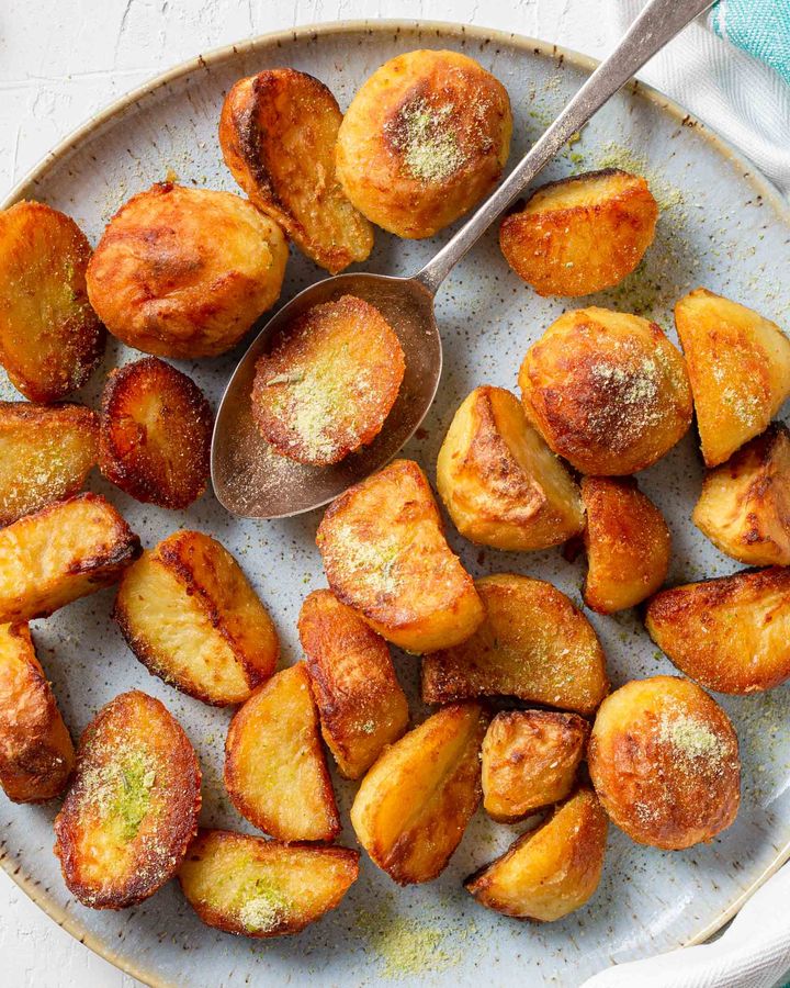 Crispy, golden roasted potatoes with green herb salt on a blue plate