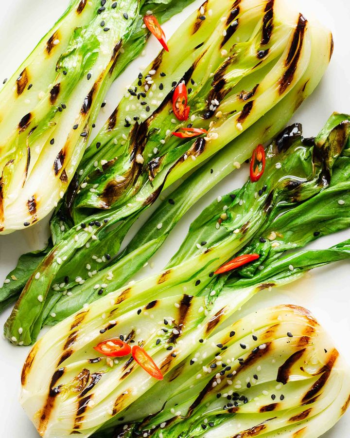 Close up of griddled pak choy halves with red chilli and sesame seeds