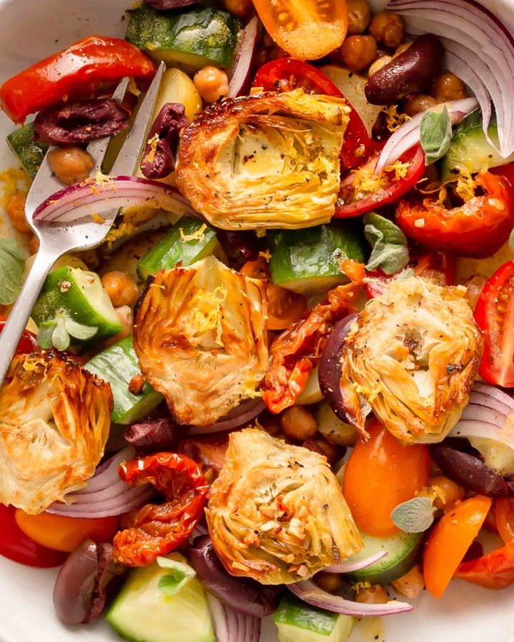 Close up of artichoke salad with chickpeas, sun-dried tomatoes, cucumber, red onion and oregano