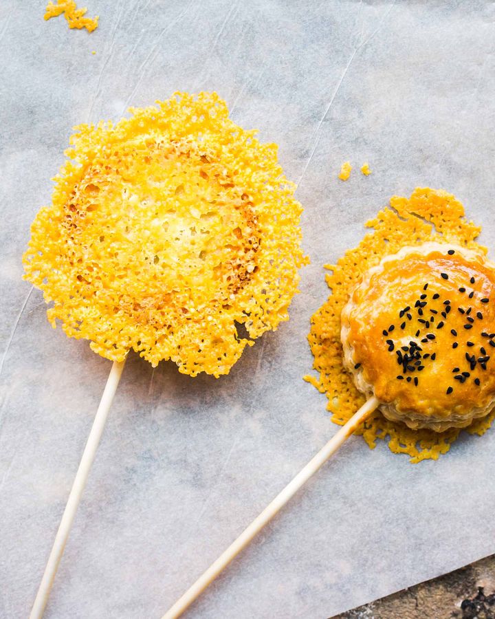 Mini pie pops on white paper sticks with crispy cheese coating