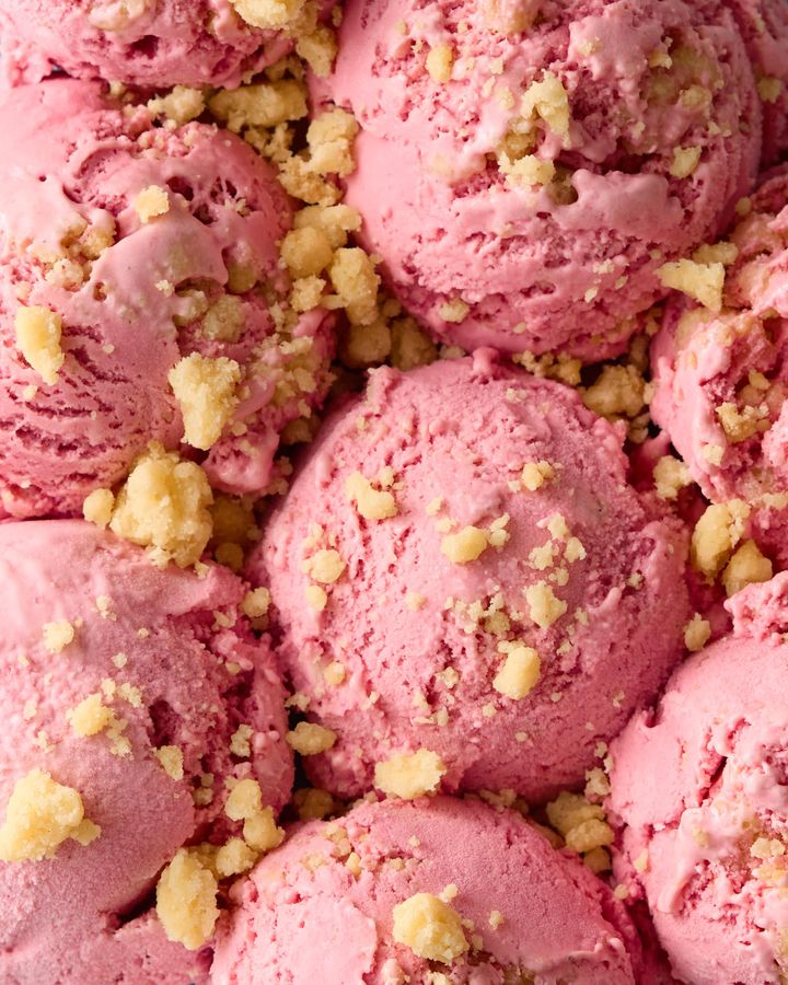 Multiple scoops of raspberry ice cream with shortbread crumbles sprinkled over