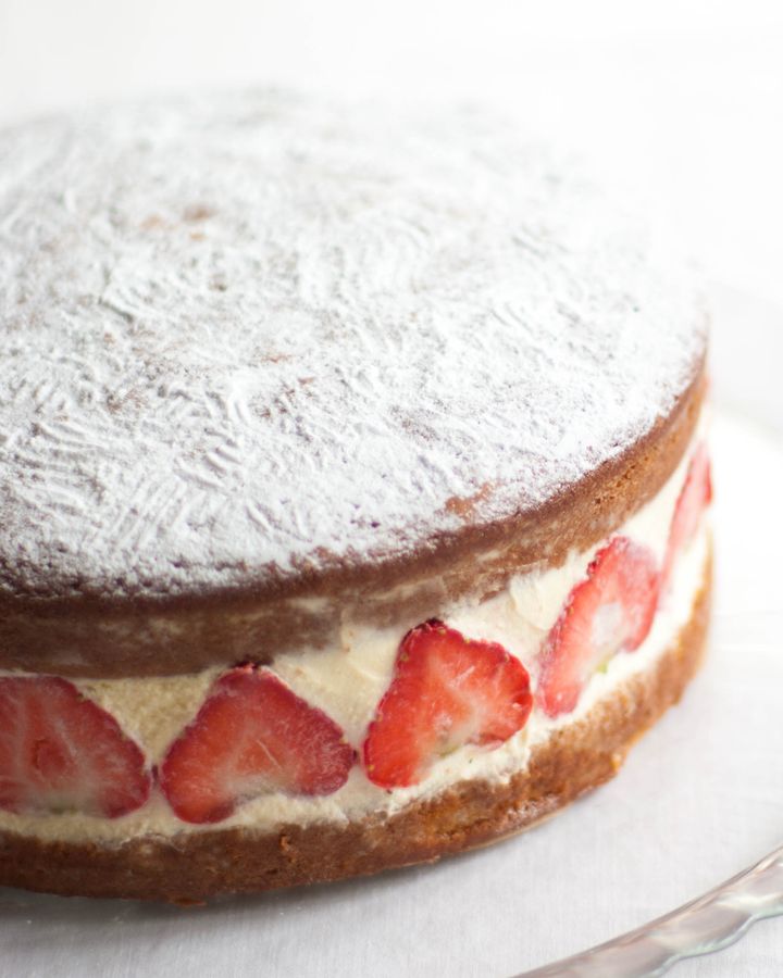Close up of Victoria sponge cake with fresh cream and sliced strawberries